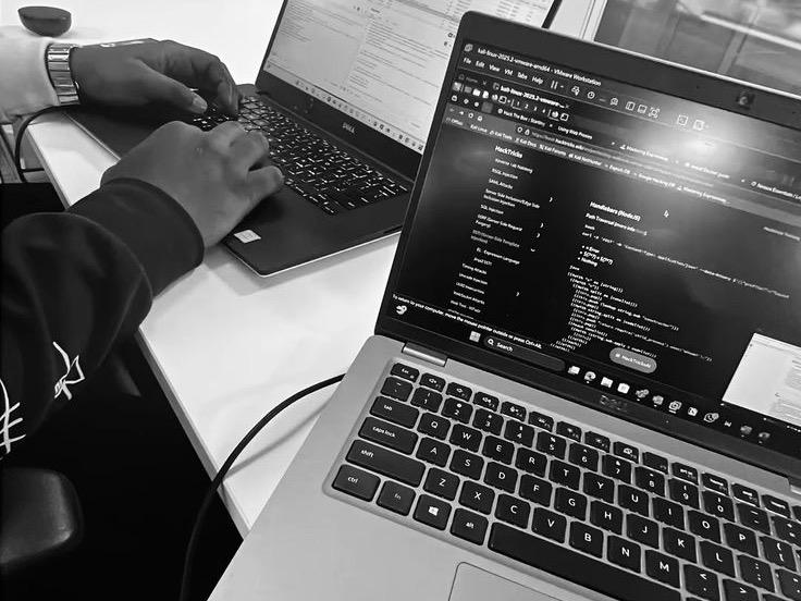 Développeur travaillant sur deux ordinateurs portables, code affiché à l'écran